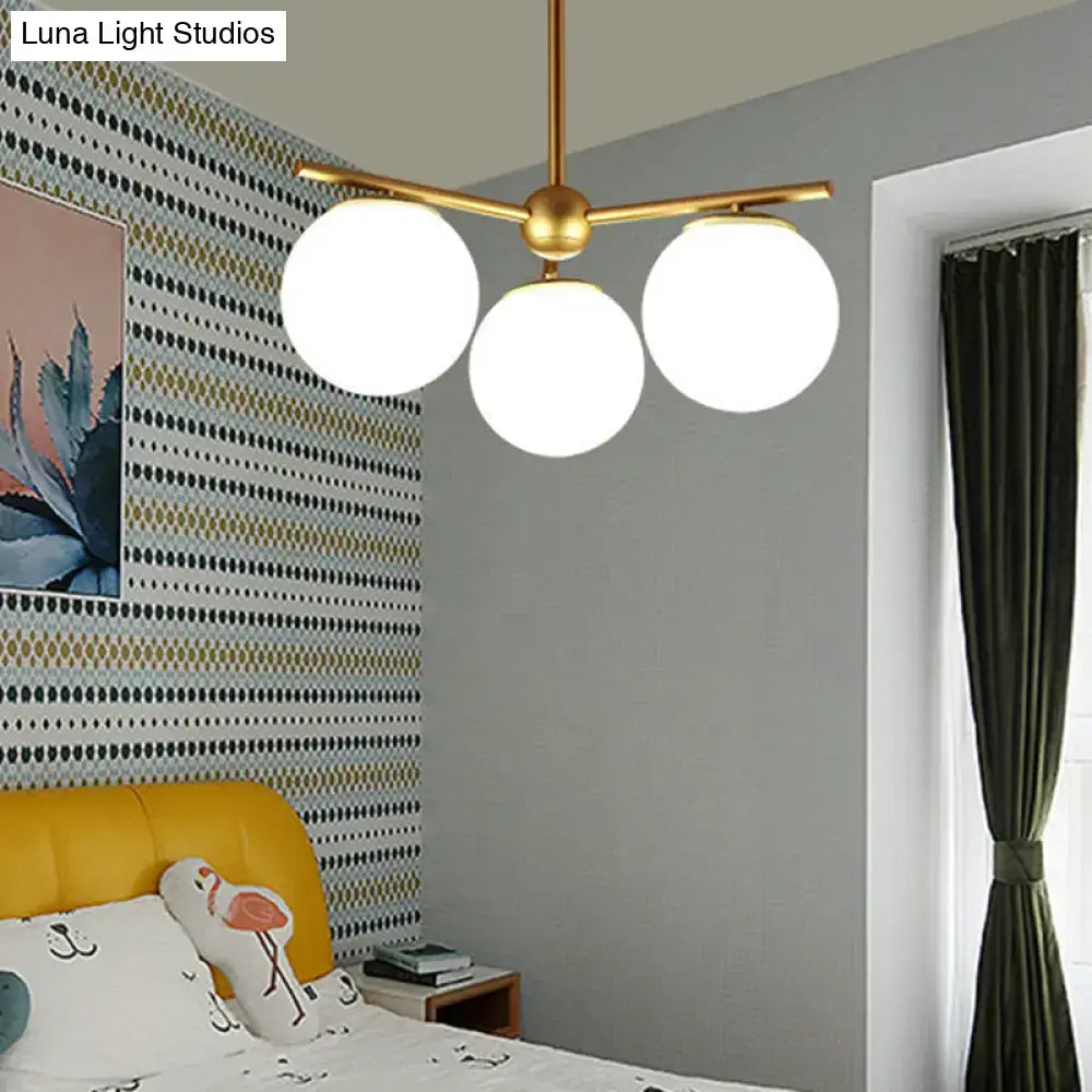 Gold-toned DecorBites modern pendant light with three white frosted glass globe shades for bedroom ceilings