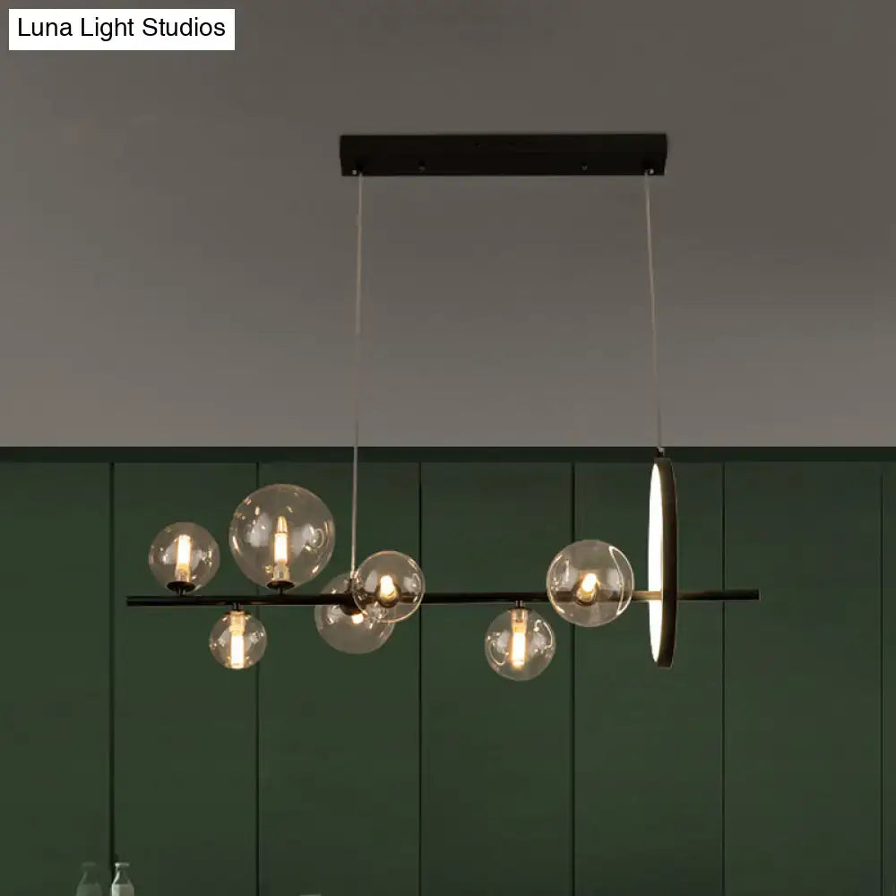 Modern black metal hanging pendant island light with seven clear glass globe bulbs and sleek circular accent light