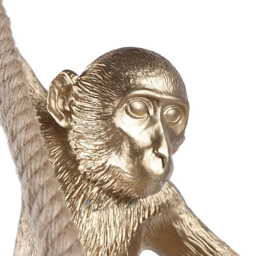 Golden metallic monkey decoration with detailed fur and expressive eyes mid-swing on hemp rope rope chandelier