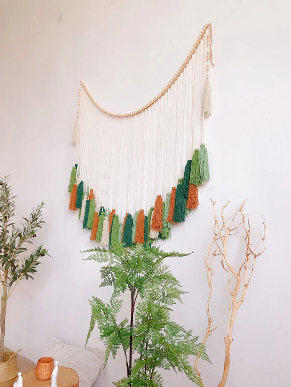A moroccan bohemian wall decor tapestry featuring a curved wooden bead arch with white green and orange tassels