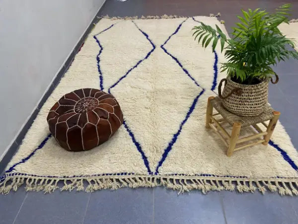 Cream-colored moroccan handmade amazigh rug with bold navy blue geometric patterns and fringed edges by decorbites