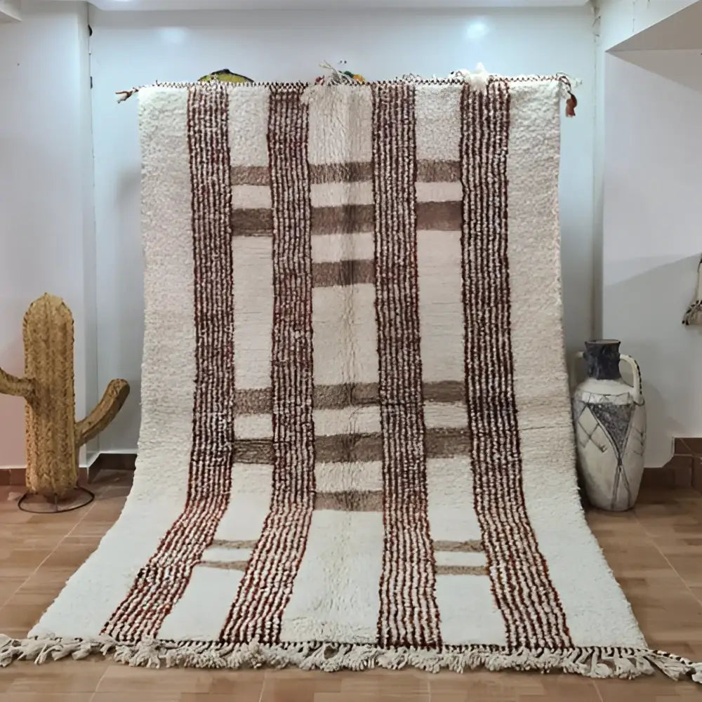 Cream-colored moroccan handmade azilal rug with thick brown vertical stripes and fringed edges by decorbites™