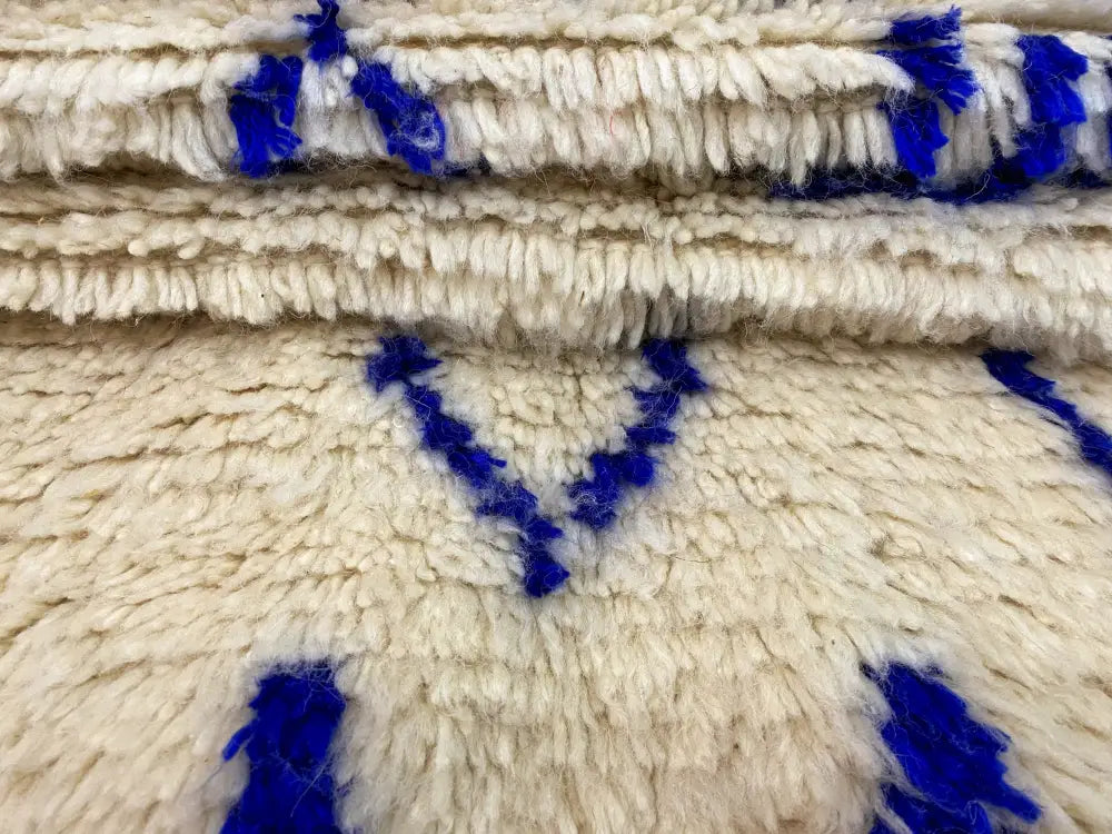 Cream-colored moroccan handmade azilal rug with bold blue geometric patterns and thick textured woolen weave 2.5m x 1.5m