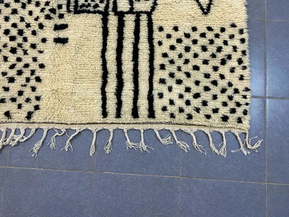 Cream-colored moroccan handmade azilal rug with black geometric patterns and fringed edges by DecorBites™ 3m x 2m
