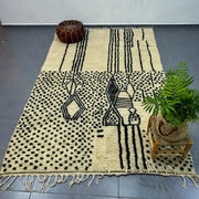 Cream-colored moroccan handmade azilal rug with bold black geometric patterns and fringed edges by decorbites 3m x 2m