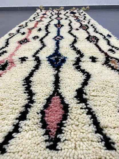 Cream-colored moroccan handmade beni ouarain rug with bold black pink and blue geometric patterns in plush wool