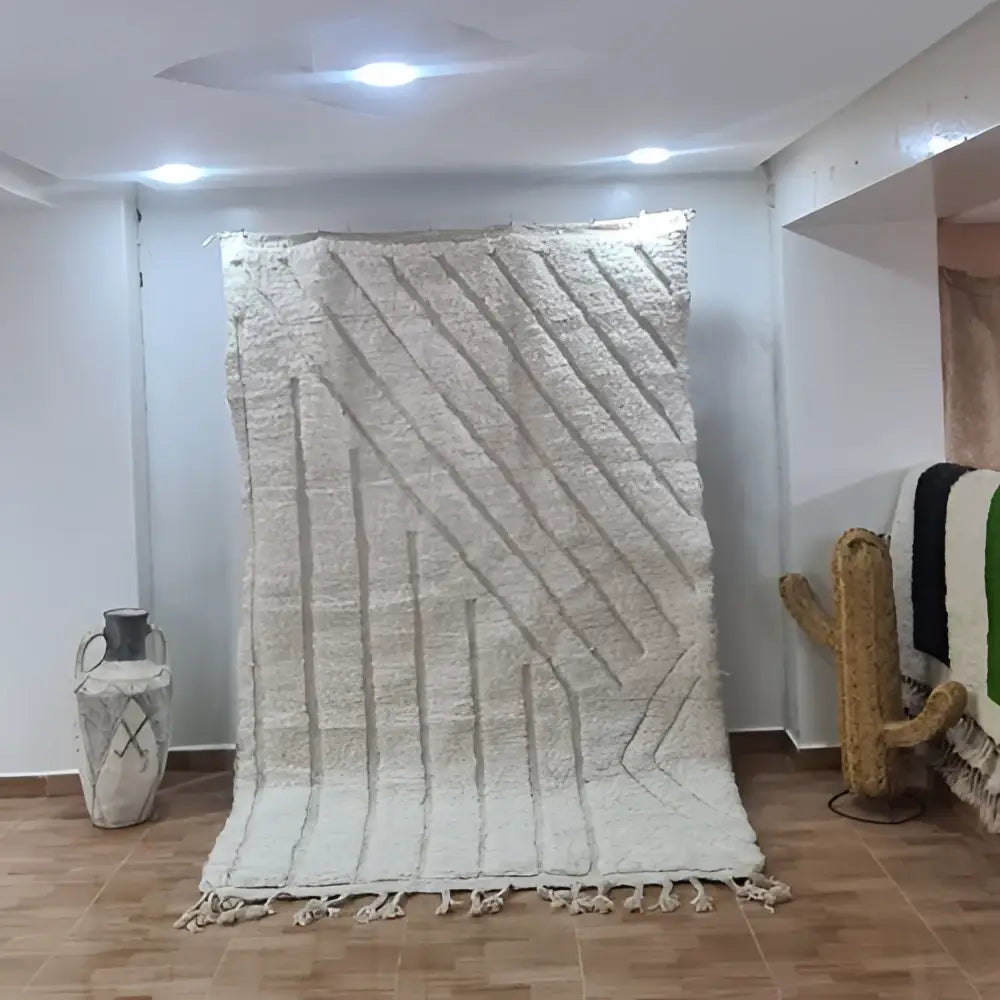 Cream-colored beni ouarain rug with textured geometric pattern and fringed edges handcrafted by skilled artisans
