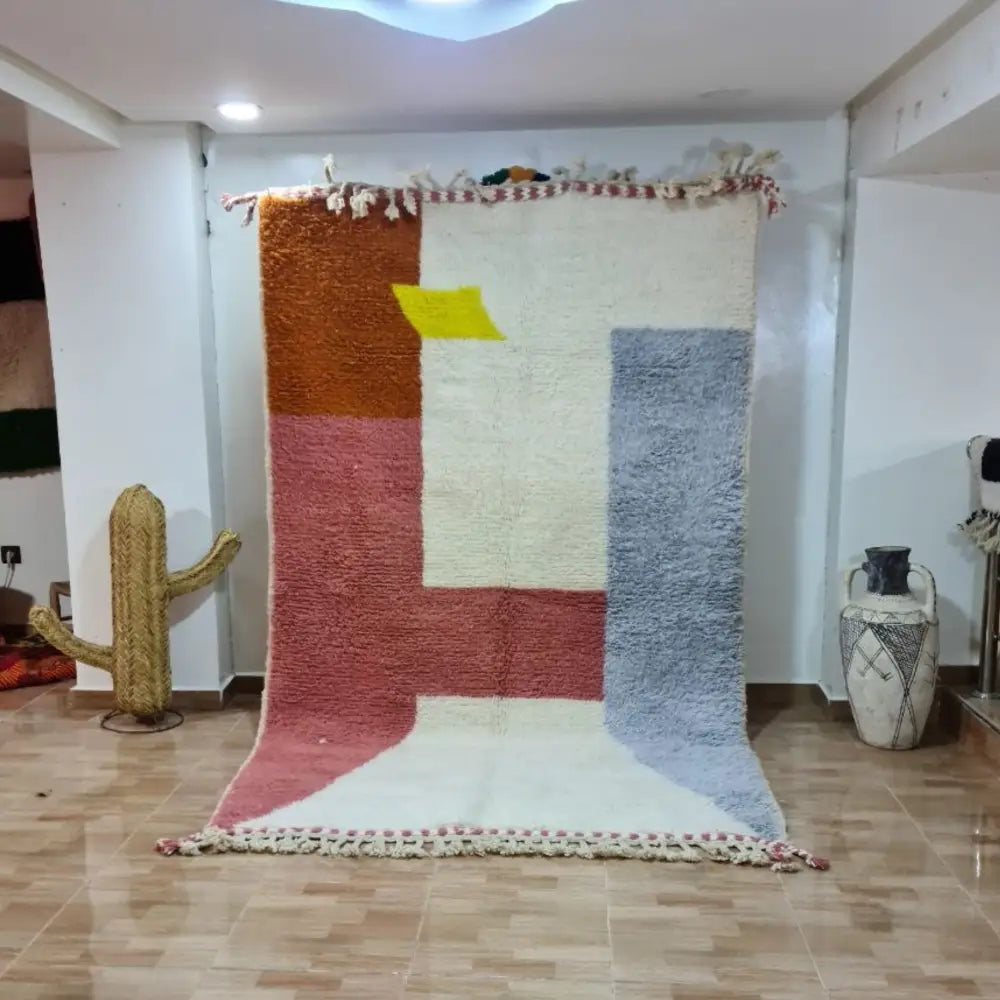 A plush moroccan handmade beni ouarain rug with a cream base and bold rust orange, dusty rose, slate blue, and yellow blocks