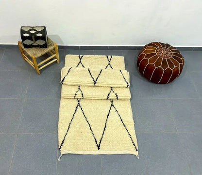 Cream-colored moroccan handmade beni ouarain rug with black geometric zigzag patterns and fringed edges 2.8m x 0.7m