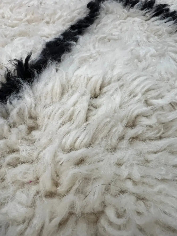Cream-colored ultra-soft curly wool moroccan handmade floor covering with bold black diagonal stripe by DecorBites™