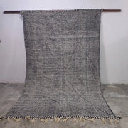 A handwoven gray and black moroccan handmade custom hanbel rug with diamond pattern and fringed natural fiber texture
