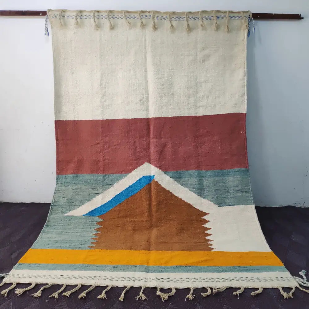 A moroccan handmade hanbel rug with cream terracotta teal brown and mustard geometric patterns and fringed edges
