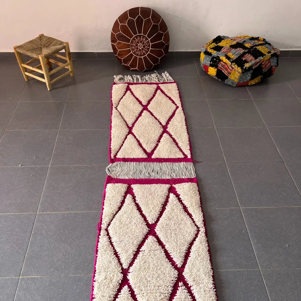 Cream-colored moroccan handmade beni ouarain rug with bold magenta diamond pattern and fringed edges from decorbites