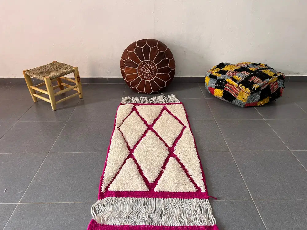 Cream-colored moroccan handmade beni ouarain rug with bold magenta geometric pattern and white fringe 1m by 70cm