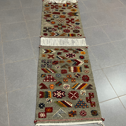 A handwoven gray moroccan handmade taznakht rug with intricate red floral and geometric patterns and fringed edges