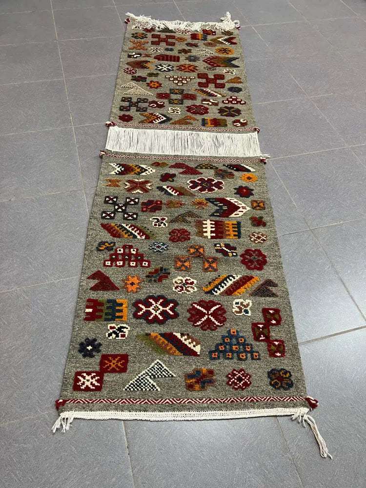 A moroccan handmade taznakht rug in gray with intricate red and orange geometric floral patterns and fringed edges