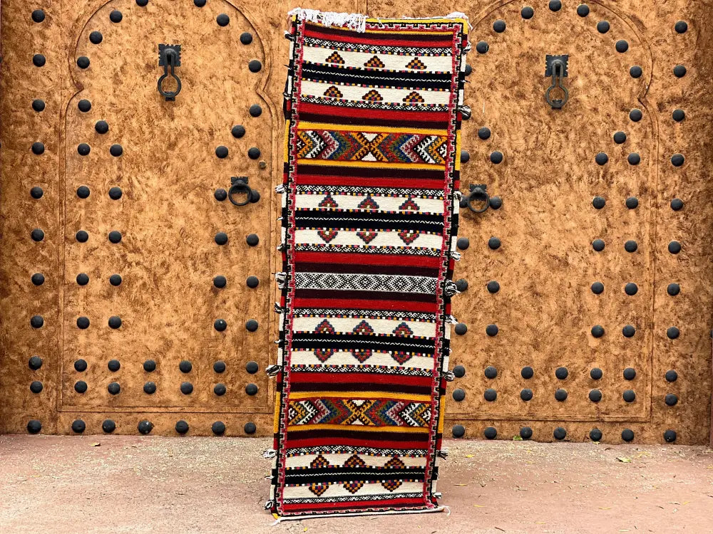 A vibrant moroccan handmade taznakht rug with bold red black white and yellow geometric diamond and zigzag patterns