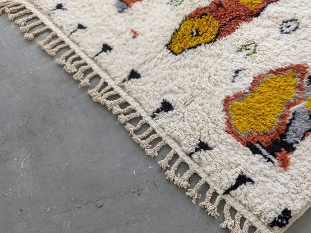 Cream-colored moroccan handmade traditional Azilal carpet with fluffy texture and bold yellow rust-orange floral motifs