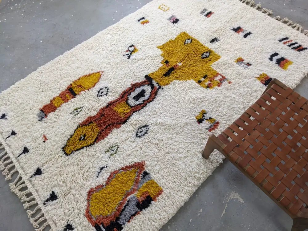 Cream-colored moroccan handmade traditional azilal carpet with fluffy texture and whimsical yellow orange animal pattern