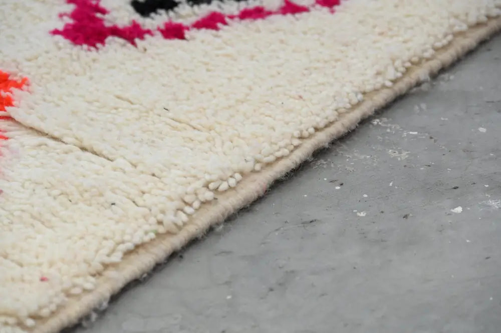Cream-colored plush wool moroccan handmade traditional azilal carpet with bold pink and black geometric edge patterns