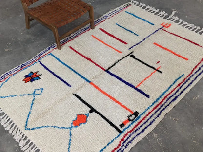 Cream-colored moroccan handmade azilal rug with bold blue red and black geometric patterns in pure natural wool