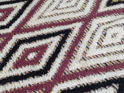 A plush moroccan handmade traditional azilal rug with maroon black and cream geometric pattern and intricate details