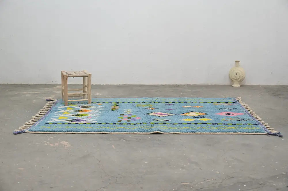 A vibrant blue DecorBites™ moroccan handmade traditional Azilal rug with colorful geometric patterns and fringed edges