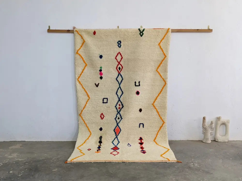 Cream-colored DecorBites™ Moroccan handmade azilal rug in pure natural wool with vibrant orange red and blue patterns