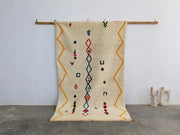 Cream-colored DecorBites™ Moroccan handmade azilal rug in pure natural wool with vibrant orange red and blue patterns