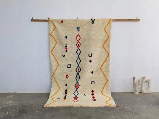 Cream-colored DecorBites™ Moroccan handmade azilal rug in pure natural wool with vibrant orange red and blue patterns