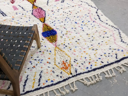 A fluffy white moroccan handmade traditional azilal rug with colorful geometric patterns and fringed edges by decorbites