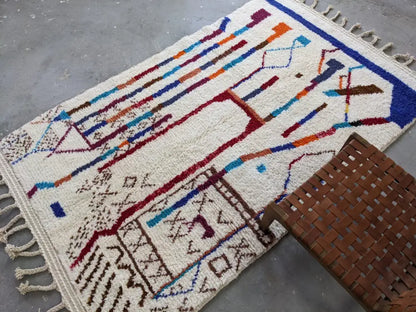 Cream-colored moroccan handmade traditional azilal rug with vibrant geometric patterns on textured wool base 250 x 150 cm
