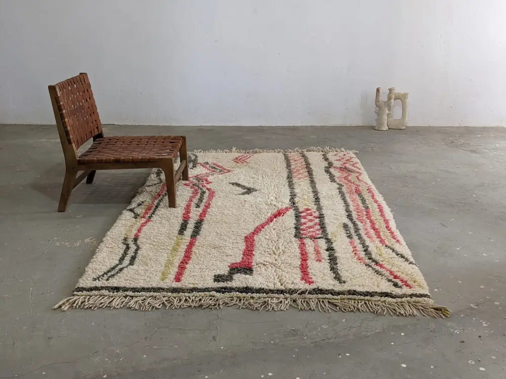 Cream-colored wool moroccan handmade traditional azilal rug with bold red black yellow geometric patterns and fringed edges