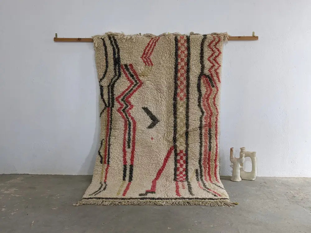 Beige moroccan handmade traditional azilal rug with bold red and black geometric patterns and fringed woolen edges