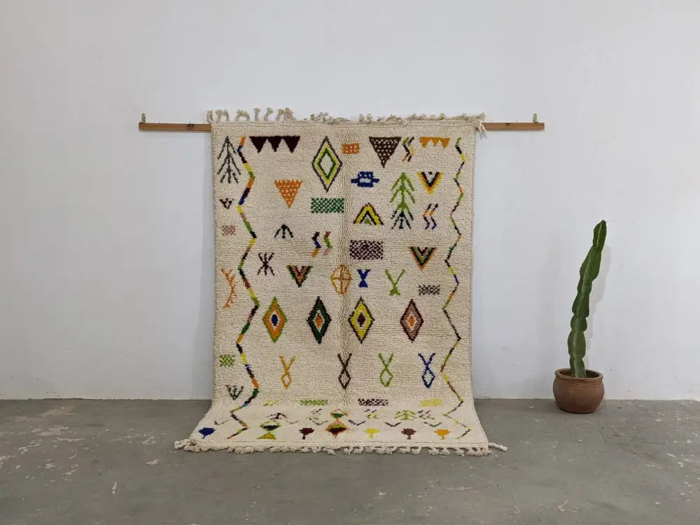 Beige moroccan handmade traditional azilal rug with black yellow green and orange geometric patterns on textured wool base