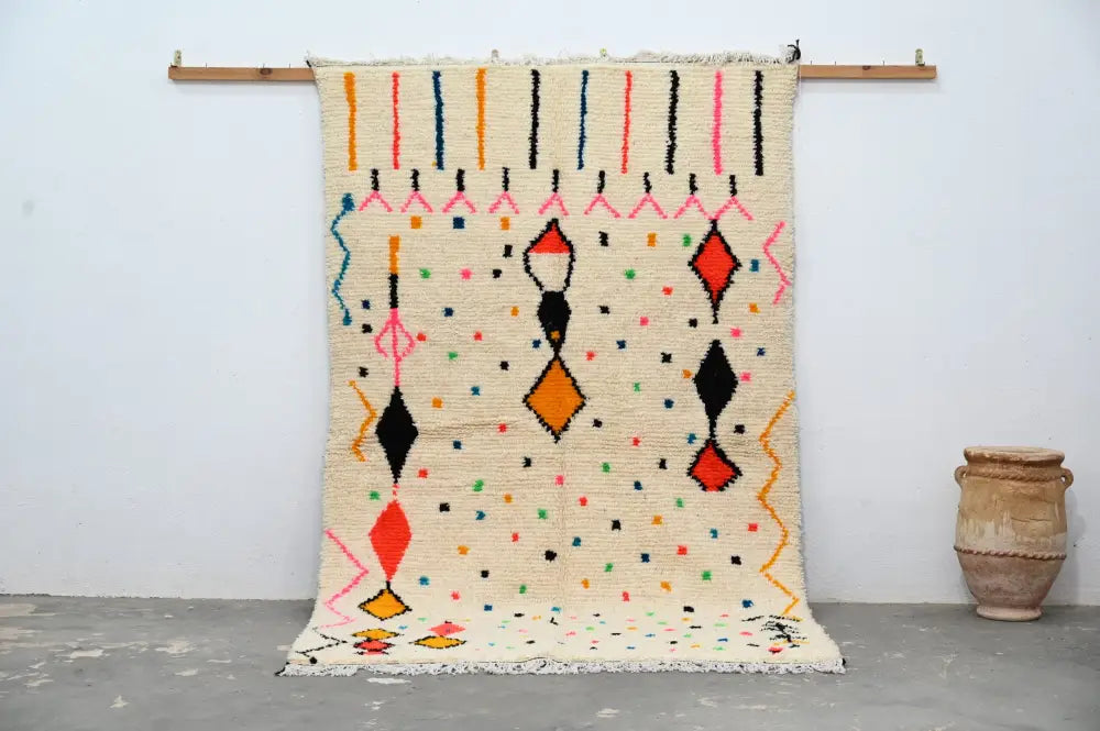 Cream-colored moroccan handmade traditional azilal rug with vibrant orange red black pink and blue geometric patterns