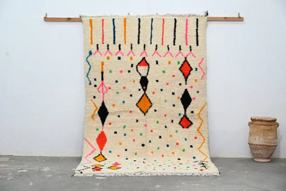 Cream-colored moroccan handmade traditional azilal rug with vibrant orange red black pink and blue geometric patterns