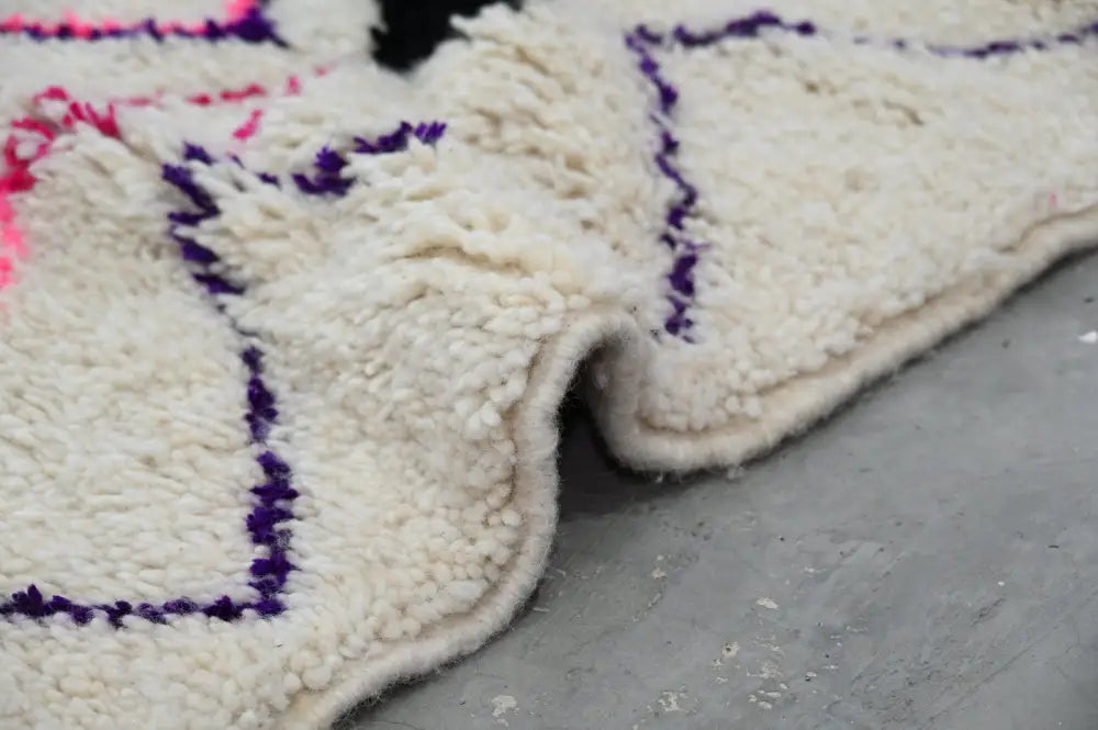 Cream-colored plush wool moroccan handmade traditional azilal rug with bold purple and pink geometric borders