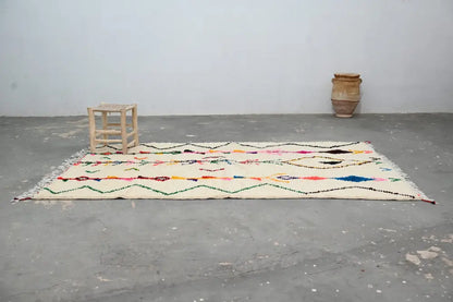 Cream-colored moroccan handmade traditional azilal rug with vibrant multicolored geometric patterns and fringed edges