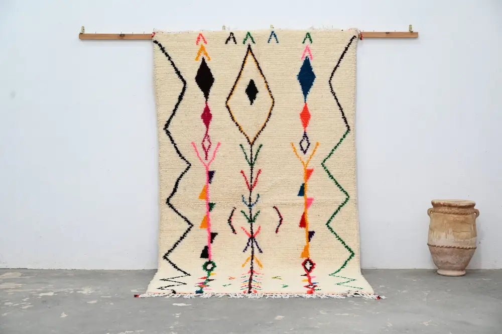 Beige moroccan handmade traditional azilal rug with vibrant geometric patterns in black red blue green and orange