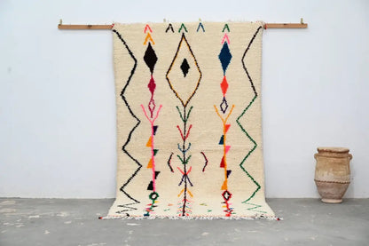 Beige moroccan handmade traditional azilal rug with vibrant geometric patterns in black red blue green and orange