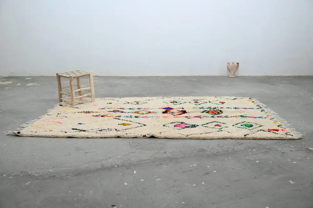 Cream-colored moroccan handmade traditional azilal rug with colorful geometric patterns and fringed edges by decorbites