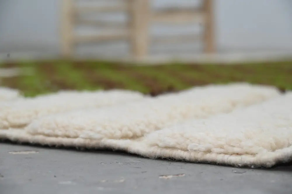 Cream-colored plush woolen moroccan handmade traditional azilal rug with soft textured surface and neatly stitched edges