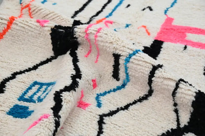 Cream-colored plush wool moroccan handmade traditional azilal rug with bold black pink and blue geometric patterns