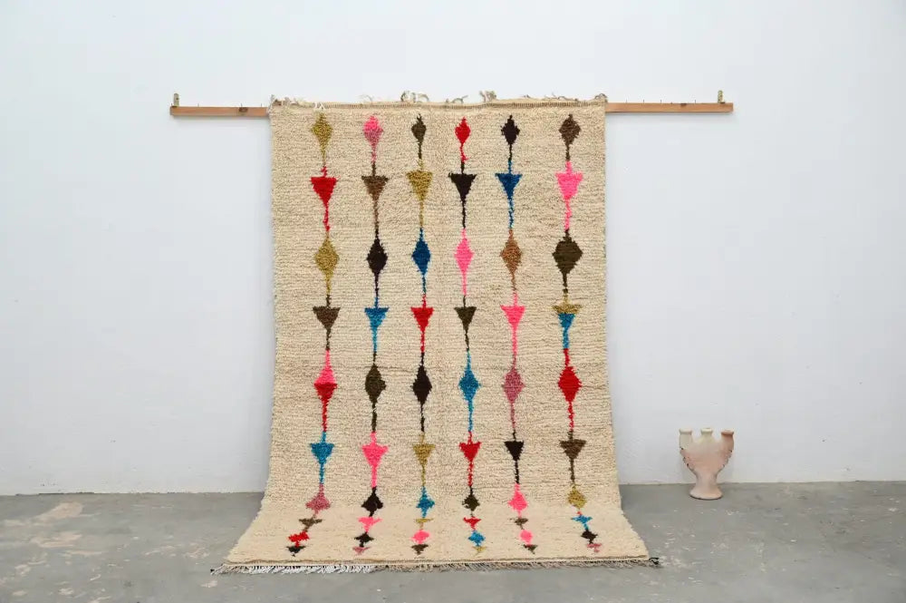 Beige woven moroccan handmade traditional azilal rug with vertical rows of colorful geometric shapes in pink red blue and brown
