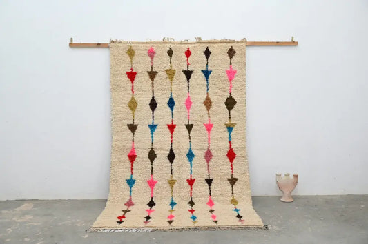 Beige woven moroccan handmade traditional azilal rug with vertical rows of colorful geometric shapes in pink red blue and brown