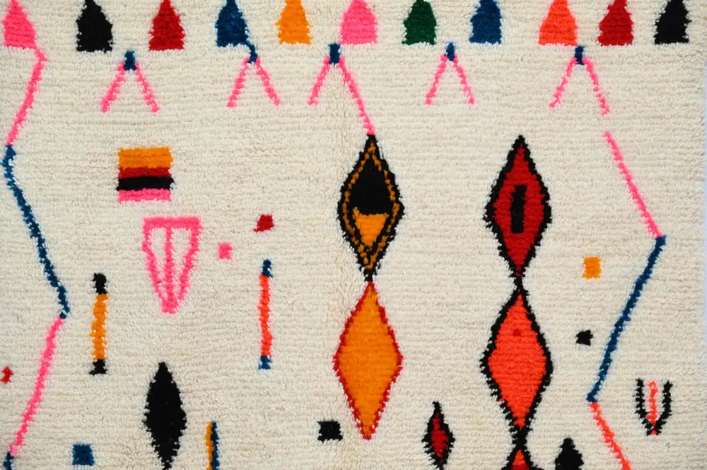 A vibrant moroccan handmade traditional azilal rug with a cream base and bold multicolor geometric patterns by decorbites