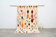 A vibrant cream-colored decorbites™ moroccan handmade traditional azilal rug with bold orange pink red and black geometric patterns