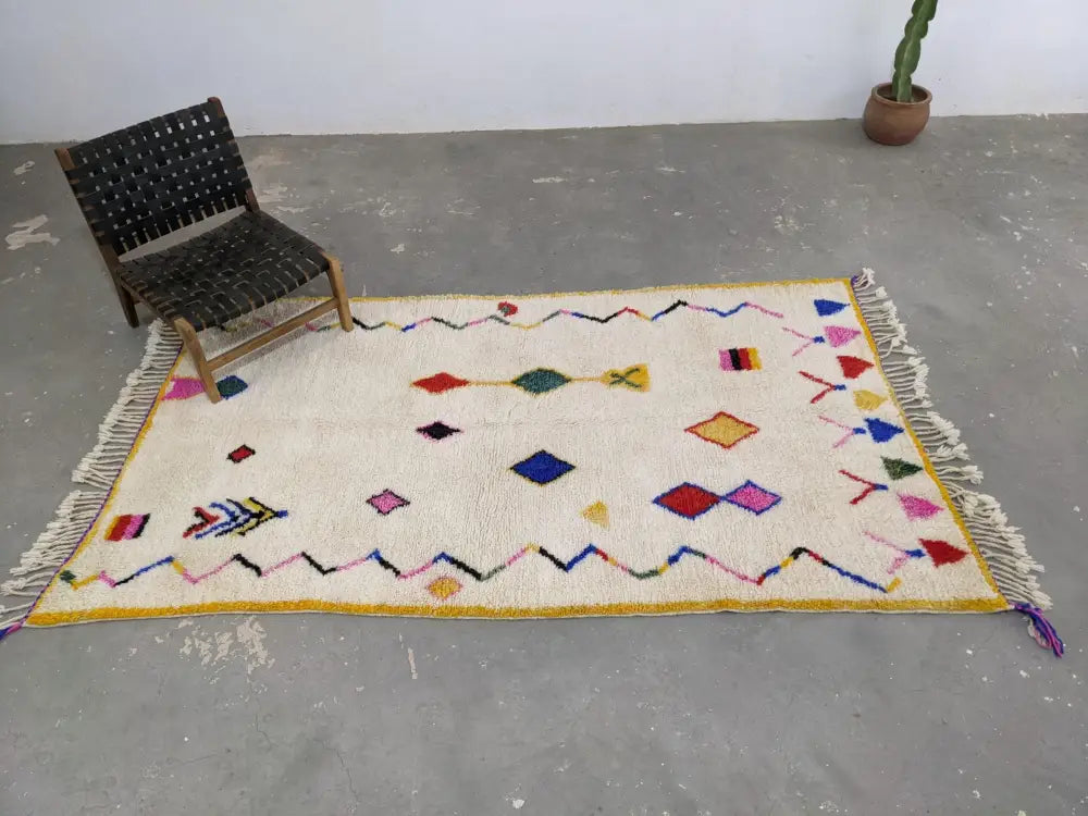 Cream-colored decorbites™ moroccan handmade traditional azilal rug with vibrant geometric patterns on textured wool base