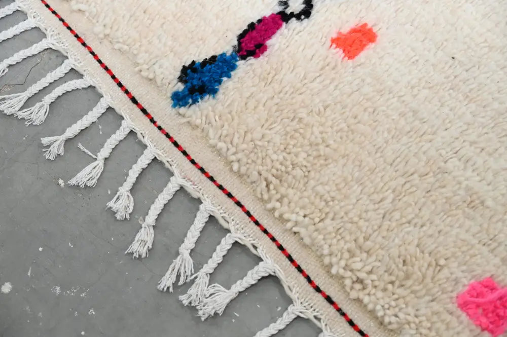 Cream-colored moroccan handmade traditional azilal rug with fluffy texture vibrant geometric patterns and white fringe